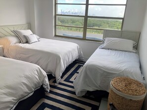 A bedroom with two beds, a window with a city view, and a striped rug. - Recently redecorated 2 bedroom Apt with Stunning Views & Prime Location (Key Biscayne)