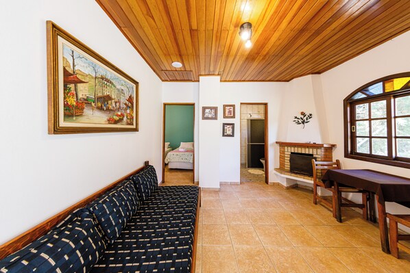 A room with a wooden ceiling, a sofa, a fireplace, and a painting on the wall. - Pousada Sonho Verde (Monte Verde)