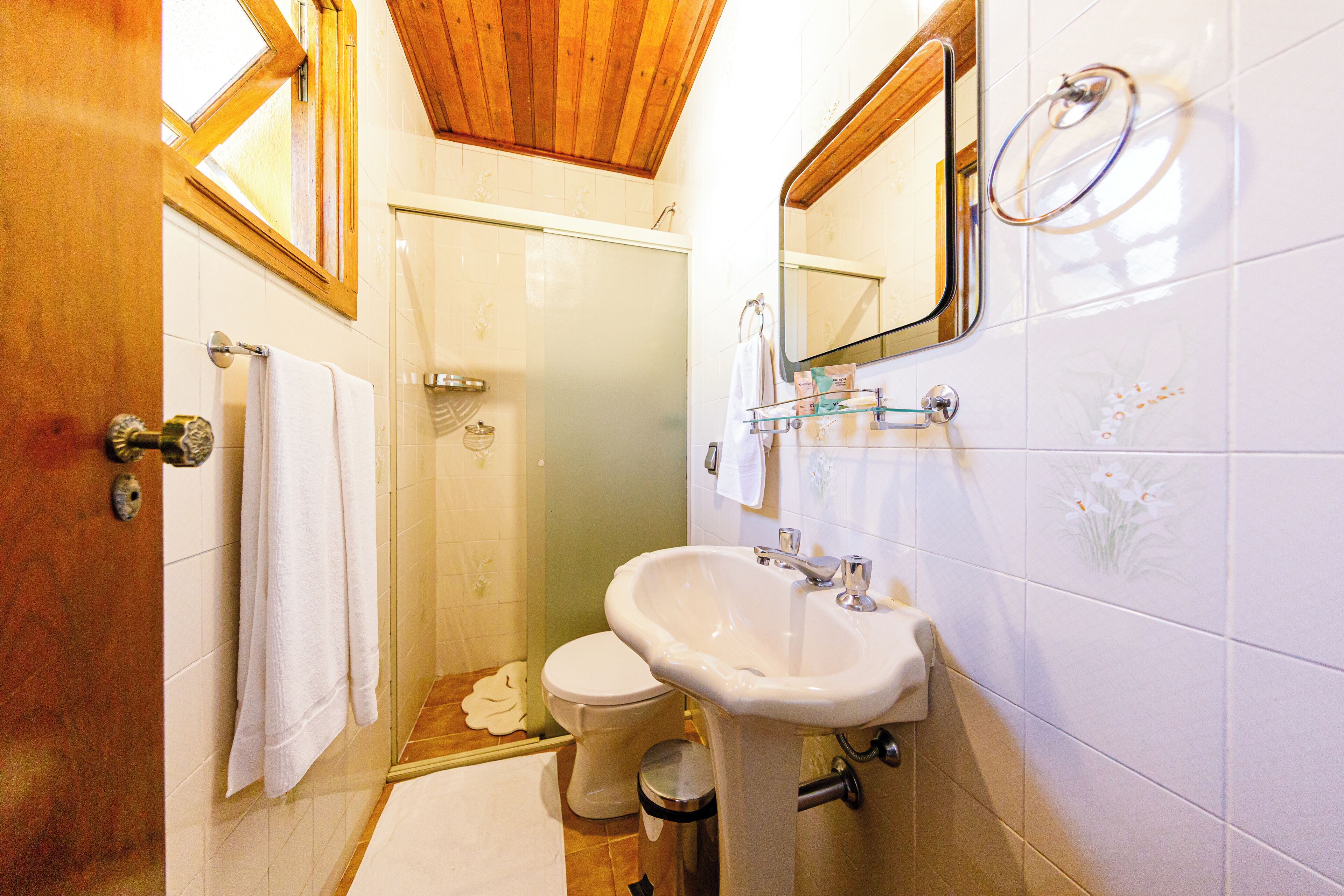 A bathroom with a shower, toilet, sink, and a mirror.