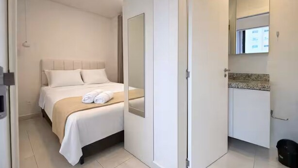Ein Hotelzimmer mit Bett, Badezimmer mit Spiegel und Waschbecken.