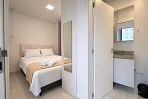 Ein Hotelzimmer mit Bett, Badezimmer mit Spiegel und Waschbecken.