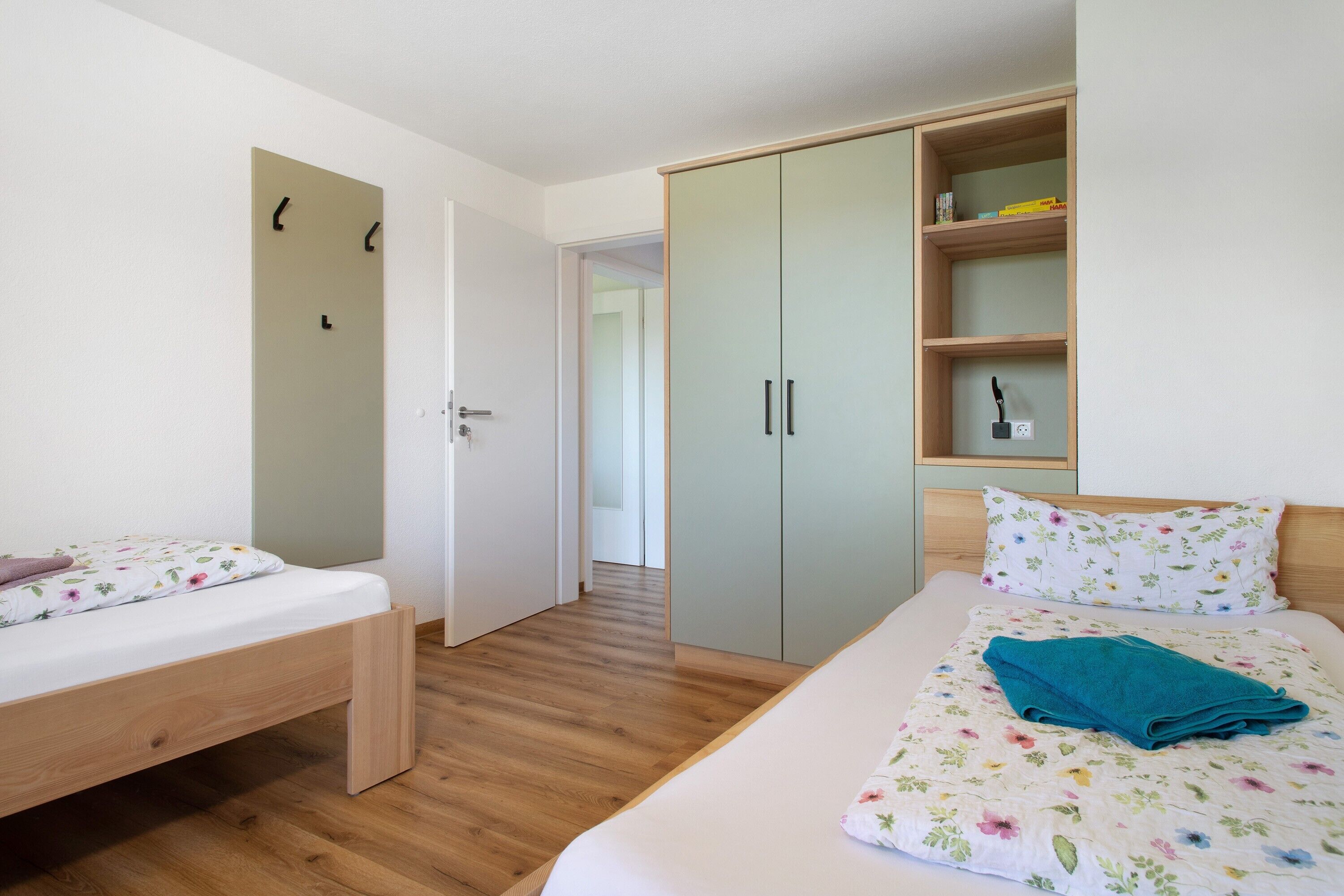 Een slaapkamer met een bed, een bankje, een kledingkast en een deur.