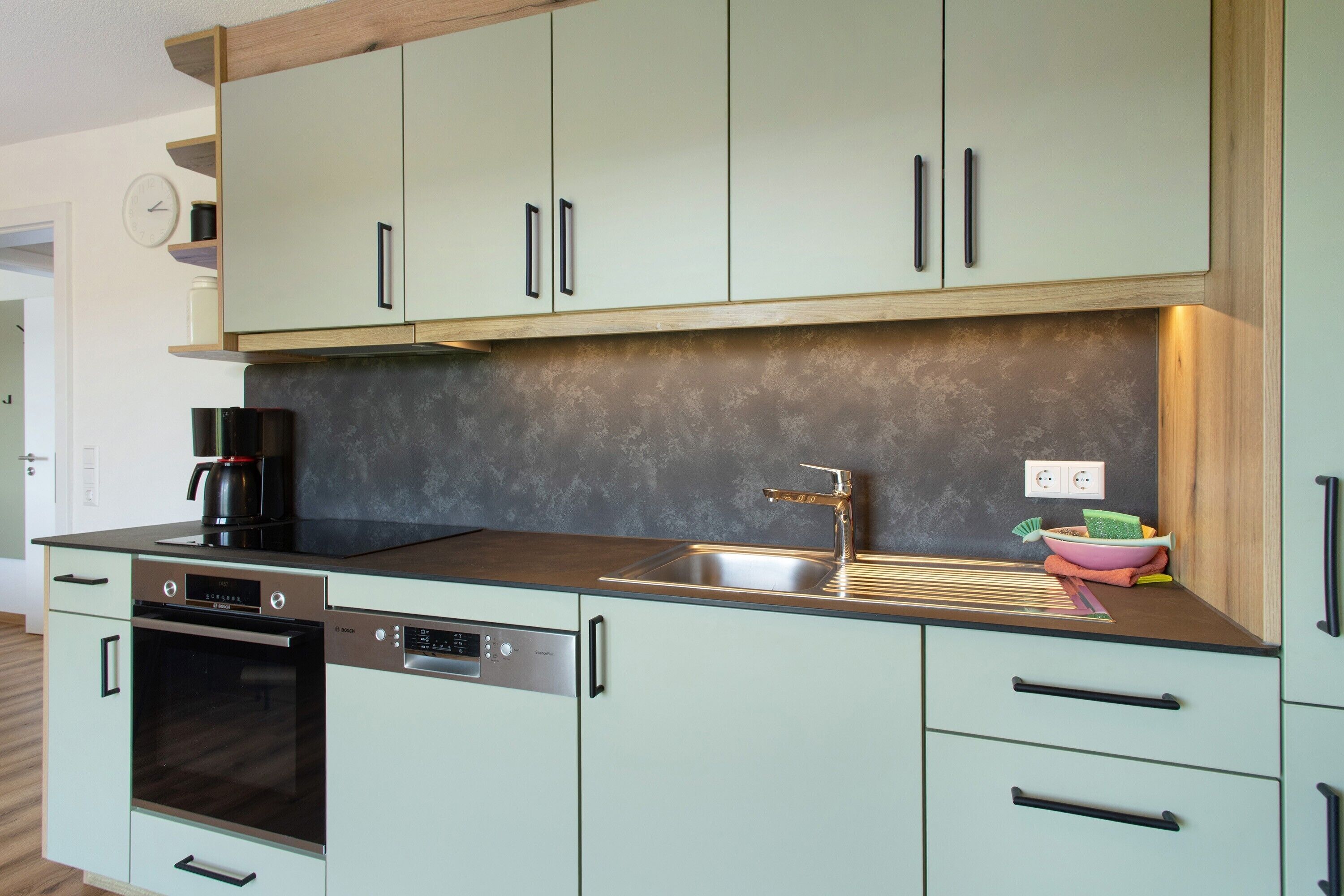 A modern kitchen with a dishwasher, oven, and a sink with a faucet.