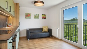 Et moderne køkken med en træbordplade og en sort sofa med pude. Tre billeder hænger på væggen.