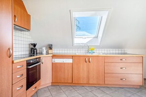 Eine moderne Küche mit Holzausbau, einem Geschirrspüler, einem Herd und einem Oberlicht.