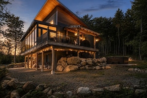 A modern two-story house with a balcony, stone foundation, and a hot tub. - Le repère de la lumière | SPA | Accès au lac (Entrelacs)