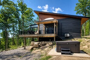 A modern cabin with a wooden deck, a hot tub, and a large window overlooking a forest. - Le repère de la lumière | SPA | Accès au lac (Entrelacs)