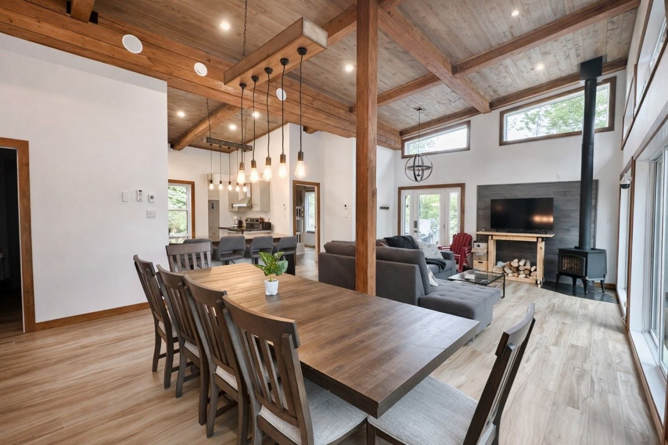 Un intérieur moderne avec une table à manger en bois, des chaises, un canapé et une cheminée.