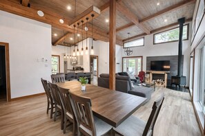 Un intérieur moderne avec une table à manger en bois, des chaises, un canapé et une cheminée.