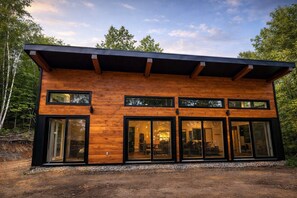 Una cabaña moderna de madera con techo plano, puertas de cristal grandes y una terraza.