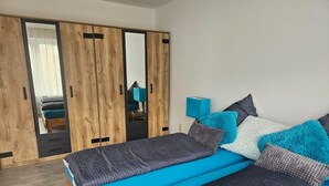Een slaapkamer met een bed, een kledingkast en een nachtkastje.