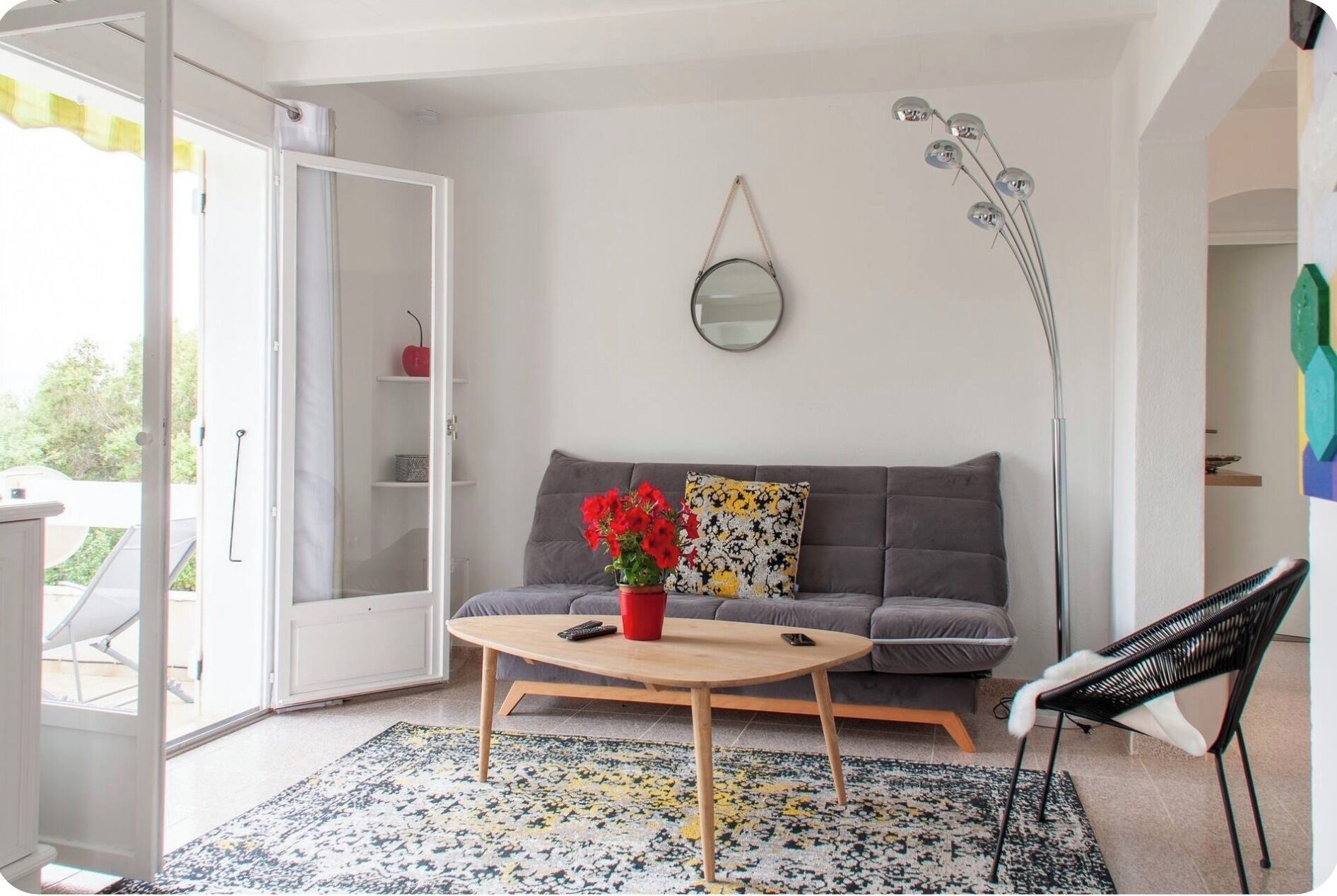 Ein Wohnzimmer mit einer Couch, einem Couchtisch, einem Sessel, einem Spiegel und einer Stehlampe.