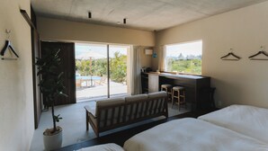 Ein Schlafzimmer mit Bett, Schreibtisch und Blick ins Freie.