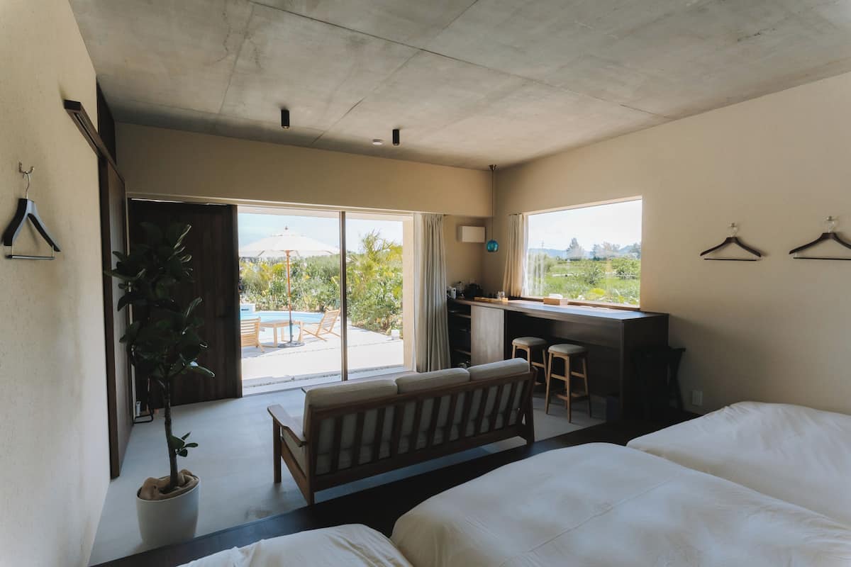 A bedroom with a bed, a desk, and a view of the outdoors.
