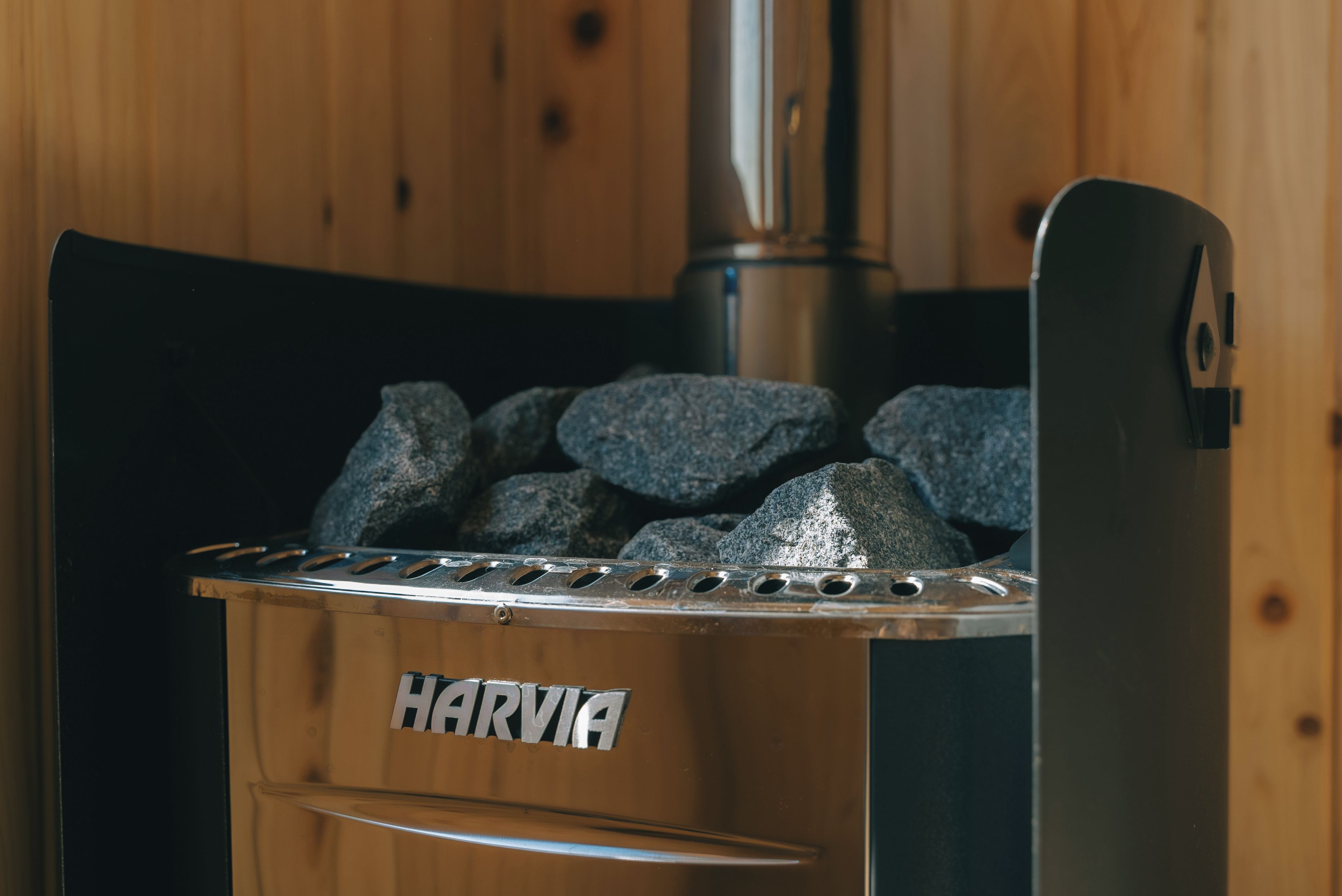 Een draagbare HARVIA grill met een metalen rooster en een houten onderstel, voor een houten achtergrond.