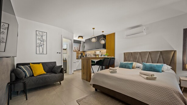 Een moderne hotelkamer met een bed, een bank, een bureau en een kitchenette.