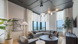 A modern living room with a sectional sofa, round coffee table, and large windows offering a view of the city. - Modern 1BR | 75ft Pool | Downtown Miami (Miami)