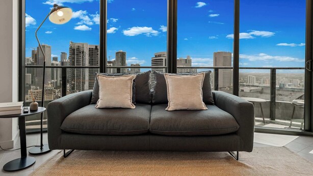 A modern living room with a city view, a sofa, a lamp, and a small table. - Modern 1BR | 75ft Pool | Downtown Miami (Miami)