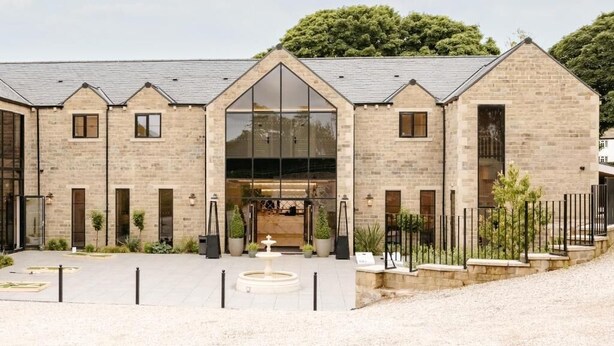 A building with a large glass entrance, stone walls, and a landscaped courtyard with a fountain. - Walton View Hotel (Bradford)