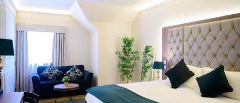 A hotel room with a bed, a sofa, a small table, and a chair.