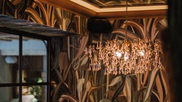 A dining area with a long table, chairs, and a chandelier.