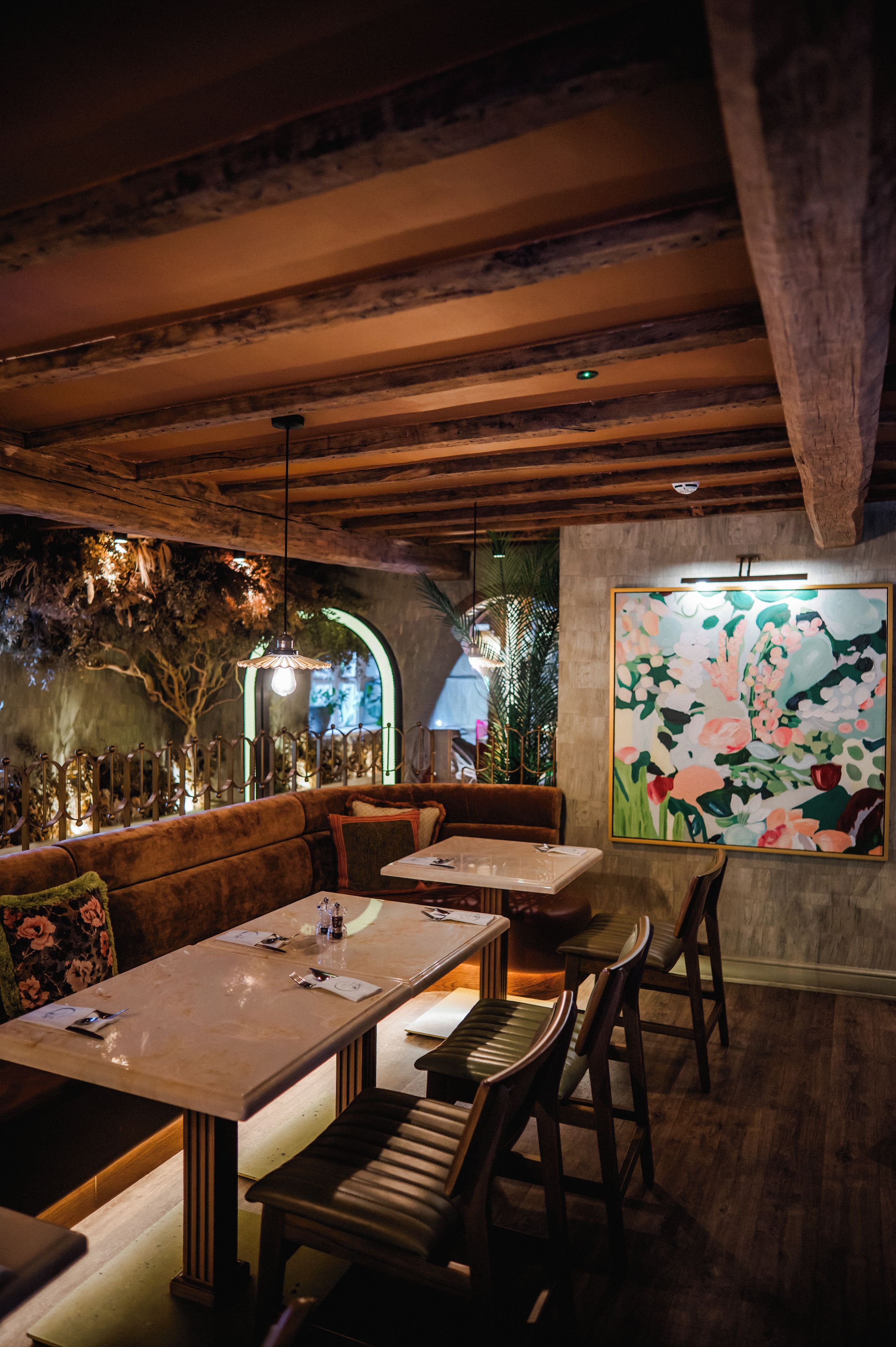 A restaurant interior with wooden beams, a mural, and a cozy seating arrangement.