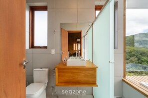 A modern bathroom with a wooden vanity, a toilet, and a large window offering a view of greenery. - Cabin With Fantastic View and Jacuzzi Vst029 (Anitapolis)