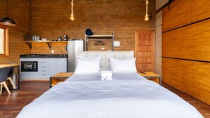 A wooden cabin-style room with a bed, bedside tables, a kitchenette, and a hanging light fixture. - Cabin With Fantastic View and Jacuzzi Vst029 (Anitapolis)