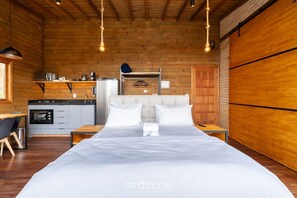 A wooden cabin-style room with a bed, bedside tables, a kitchenette, and a hanging light fixture. - Cabin With Fantastic View and Jacuzzi Vst029 (Anitapolis)