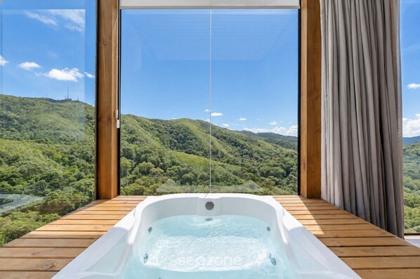 A hot tub on a wooden deck with a scenic view of green hills and a clear sky. - Cabin With Fantastic View and Jacuzzi Vst029 (Anitapolis)