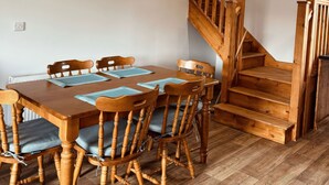 A dining area with a wooden table and chairs, a staircase, and a radiator.