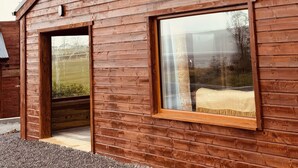 A wooden cabin with a large window, a door, and a small porch area.