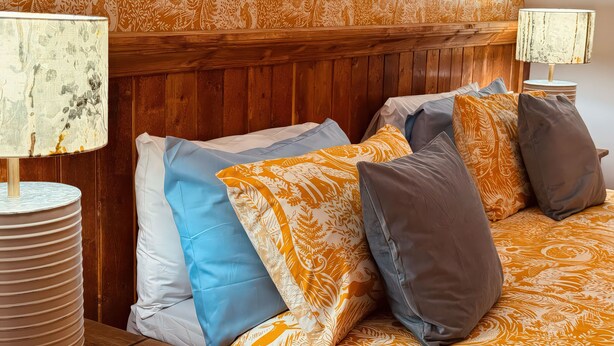 A bed with patterned bedding, a wooden headboard, and two lamps.