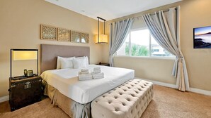 A hotel room with a bed, bedside table, lamp, and a view of the outdoors. - Spacious Luxury 4BR Suite Near Disney (Kissimmee)
