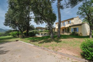 A two-story house with a covered patio, surrounded by trees and a grassy lawn. - 4 BEDROOM VILLA WITH PRIVATE POOL AND GARDEN (N°443) (La Motte)