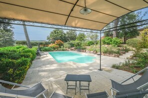 Un espace extérieur abrité comprenant une piscine, des chaises longues et une table.