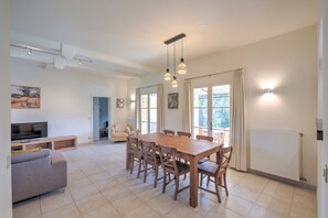 A spacious living area with a dining table, sofas, and a TV. - 4 BEDROOM VILLA WITH PRIVATE POOL AND GARDEN (N°443) (La Motte)
