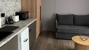Eine moderne Küche mit integriertem Geschirrspüler, einem Holzkasten, einem grauen Sofa und einem runden Couchtisch.