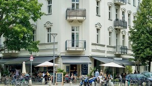 Ein Gebäude mit mehreren Balkonen, Sitzgelegenheiten im Freien und Fahrrädern vor der Tür.