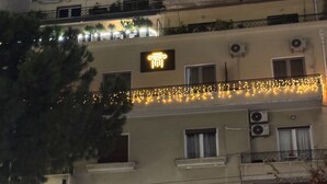 En byggnad med flera våningar, balkonger, luftkonditioneringsanordningar och en skylt med en symbol som föreställer en kolumn.