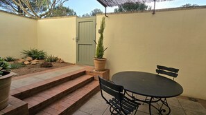 Un patio con tavolo e sedie, una porta e una pianta in vaso.
