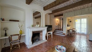 Ein Wohnzimmer mit Kamin, Fernseher und einer Treppe, die in einen anderen Raum führt.
