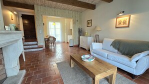 Ein Wohnzimmer mit Kamin, einem weißen Sofa, einem Holztisch und einem gemusterten Teppich.