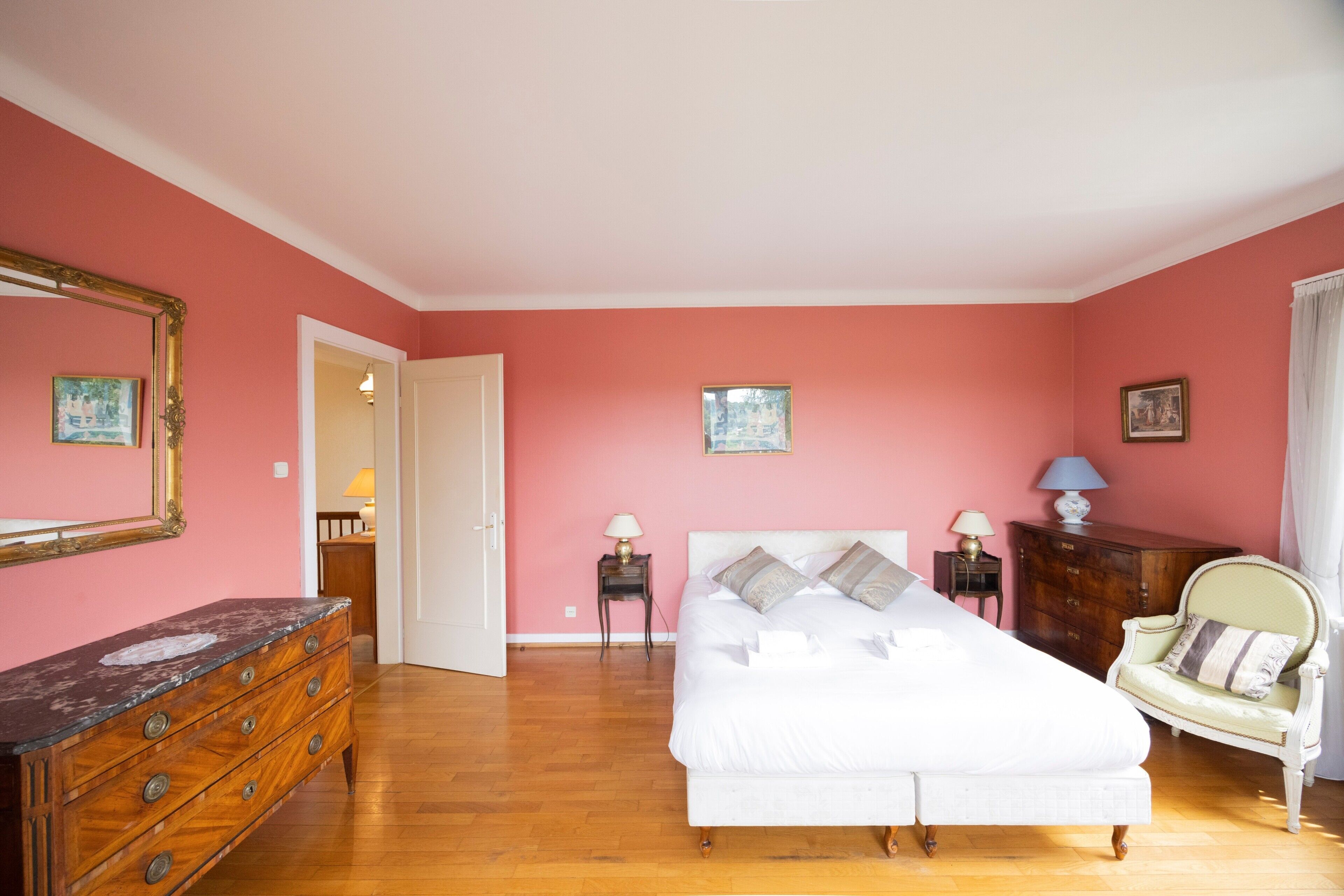 A bedroom with a bed, dresser, chair, and two nightstands with lamps.