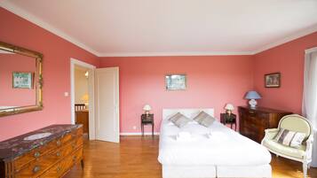 A bedroom with a bed, dresser, chair, and two nightstands with lamps.