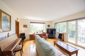 A living room with a piano, a sofa, a television, and large windows. - Maison Bellevue, private terrace with view (Brunstatt-Didenheim)