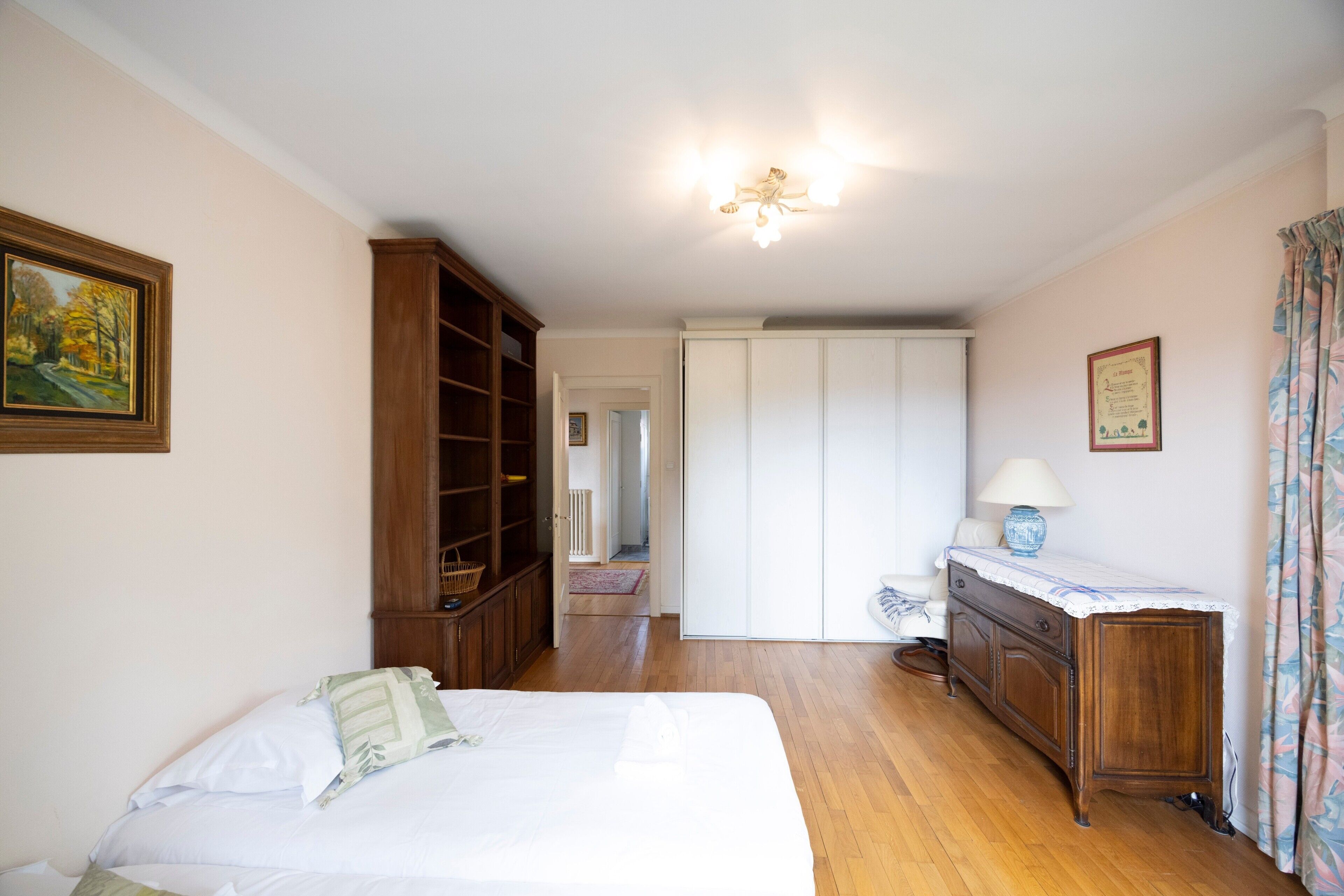 Une chambre à coucher avec un lit, une armoire en bois et un bureau avec une lampe.