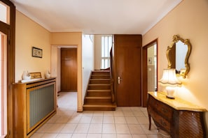A hallway with a wooden staircase, a console table with a lamp, and a mirror on the wall. - Maison Bellevue, private terrace with view (Brunstatt-Didenheim)