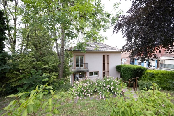 Ein modernes Haus mit Balkon, umgeben von üppiger Vegetation und einem gepflegten Garten.