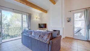 Una sala de estar con sofá, televisión, chimenea y ventanas amplias.